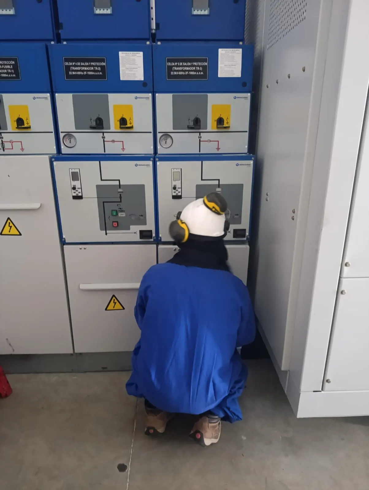 Técnico con casco realizando pruebas frente a celdas de media tensión
